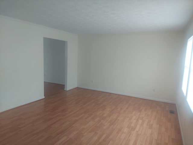 spare room featuring light hardwood / wood-style floors and a textured ceiling