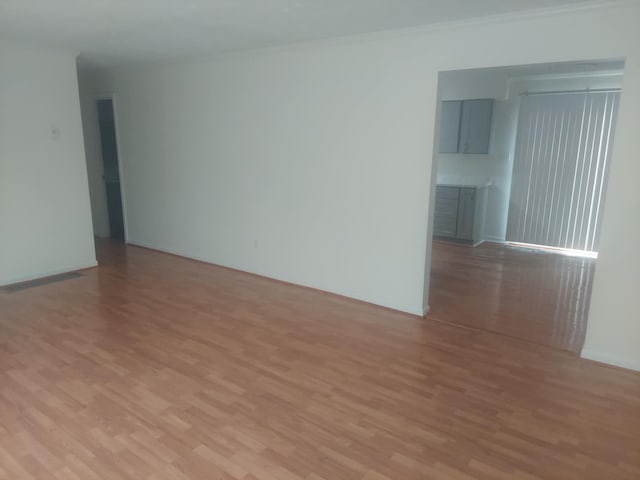 empty room featuring light hardwood / wood-style floors and crown molding