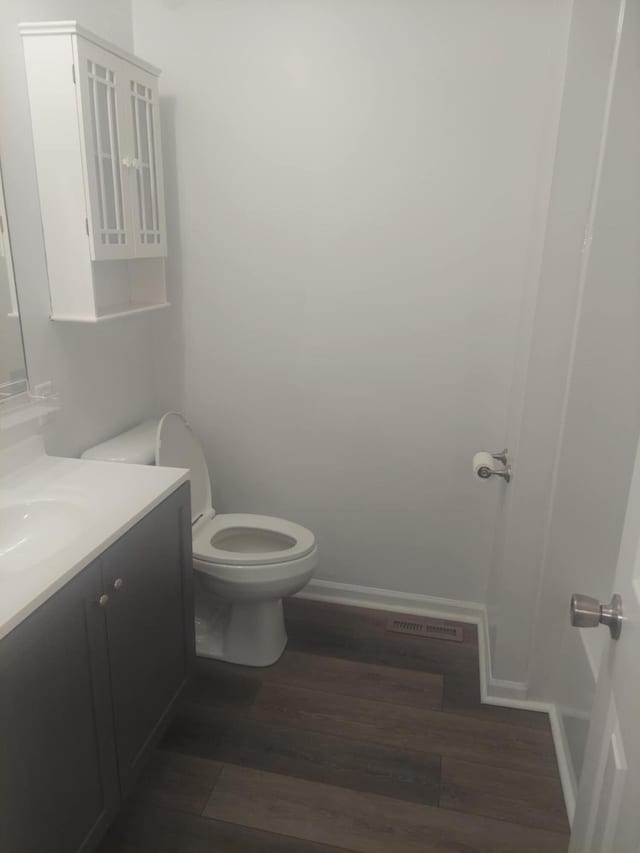 bathroom with toilet, vanity, and hardwood / wood-style flooring