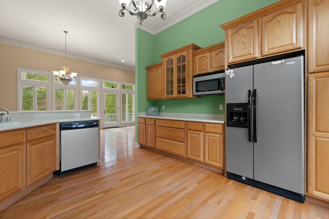 kitchen with sink, crown molding, a notable chandelier, pendant lighting, and stainless steel appliances