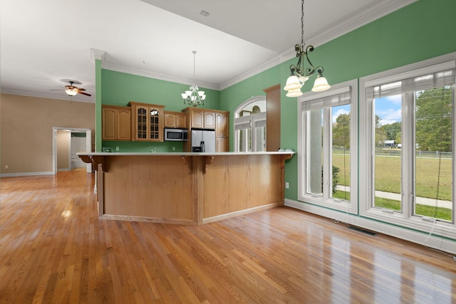 kitchen featuring crown molding, hanging light fixtures, light hardwood / wood-style flooring, appliances with stainless steel finishes, and kitchen peninsula