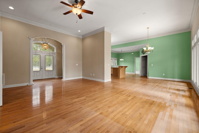 unfurnished living room featuring decorative columns, crown molding, ceiling fan with notable chandelier, and light hardwood / wood-style floors