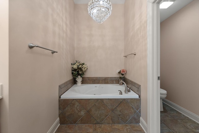 bathroom featuring a relaxing tiled tub, toilet, and an inviting chandelier