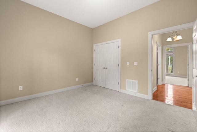 unfurnished bedroom featuring carpet, a notable chandelier, and a closet