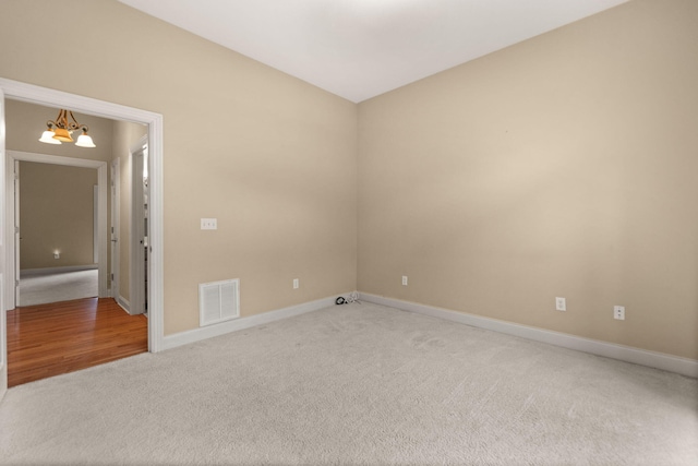 empty room with carpet flooring and a chandelier