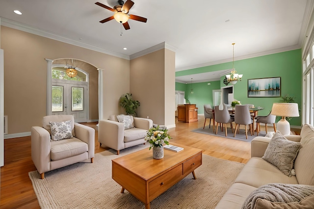 living room with ceiling fan with notable chandelier, ornamental molding, light hardwood / wood-style floors, and ornate columns