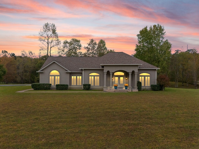 view of front of property with french doors and a lawn