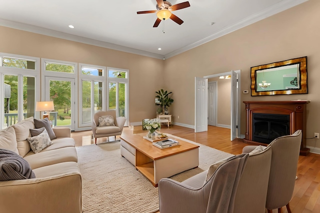 living room featuring ornamental molding, ceiling fan, and light wood-type flooring