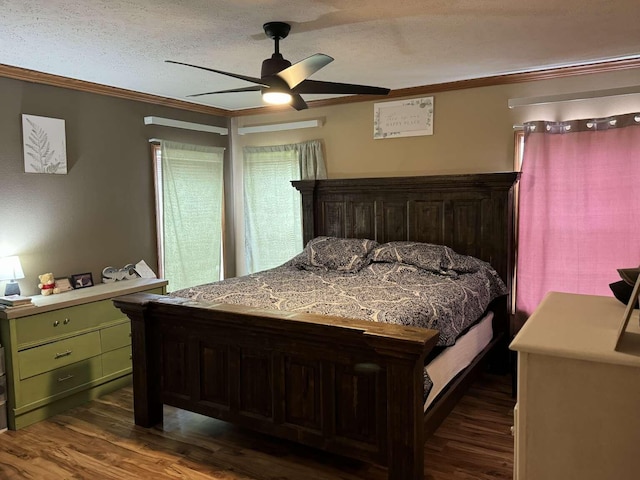 bedroom with dark wood-type flooring, ceiling fan, ornamental molding, and a textured ceiling