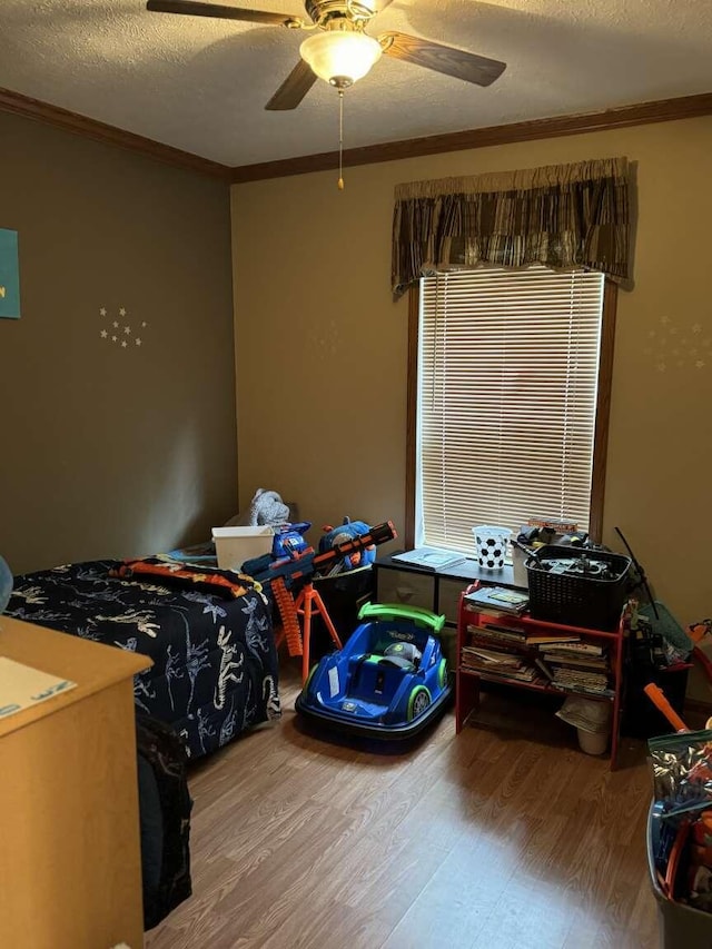 bedroom featuring a ceiling fan, a textured ceiling, wood finished floors, and crown molding