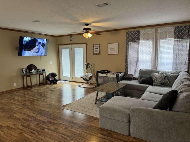 living room featuring visible vents, a textured ceiling, crown molding, and wood finished floors