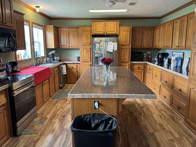 kitchen featuring light wood-type flooring, ceiling fan, a kitchen island, and stainless steel appliances