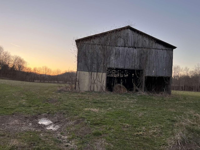 outdoor structure at dusk with an outbuilding, a lawn, and a barn