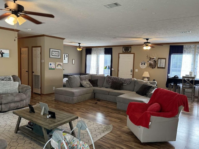 living area featuring ornamental molding, wood finished floors, visible vents, and a textured ceiling