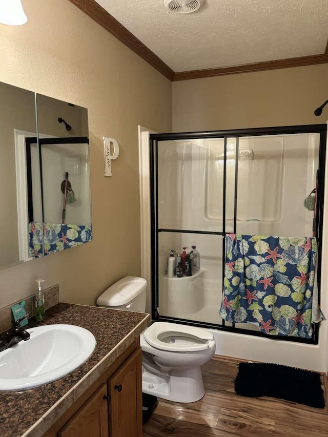 full bathroom featuring toilet, hardwood / wood-style floors, vanity, a textured ceiling, and bath / shower combo with glass door