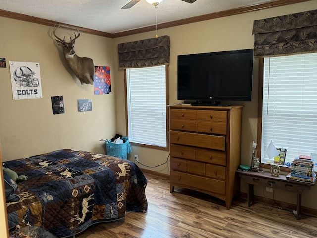 bedroom featuring a textured ceiling, crown molding, ceiling fan, and hardwood / wood-style flooring