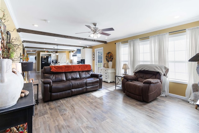 living room featuring light wood-type flooring, ceiling fan, beamed ceiling, and ornamental molding