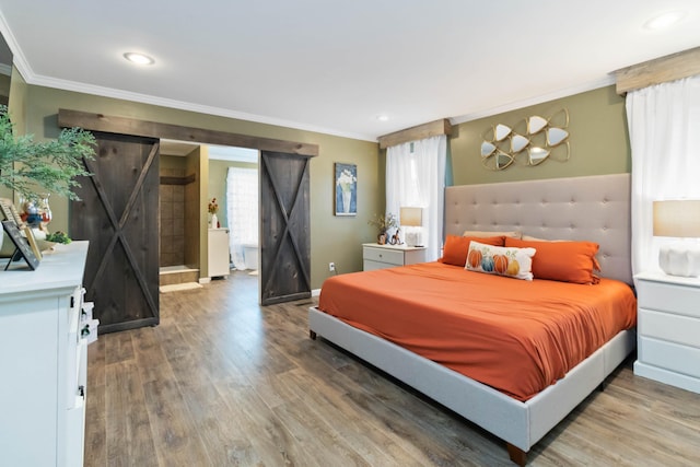 bedroom with crown molding, multiple windows, hardwood / wood-style floors, and a barn door