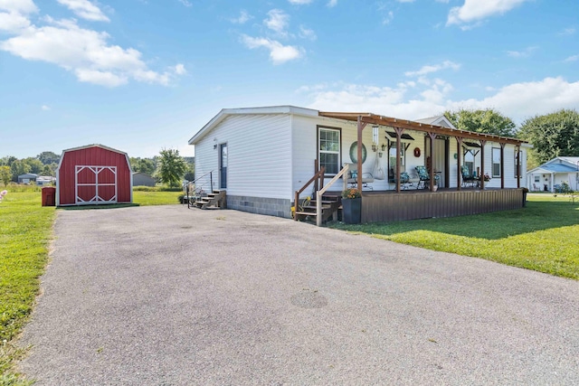 view of front of house with a front yard, a storage unit, and a porch