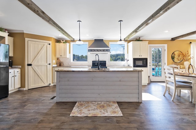 kitchen featuring wall chimney exhaust hood, beamed ceiling, dark wood-type flooring, and pendant lighting