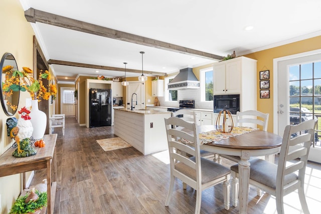 dining space featuring hardwood / wood-style flooring, ornamental molding, beam ceiling, and sink