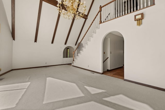 interior space featuring beamed ceiling, carpet flooring, a chandelier, and high vaulted ceiling