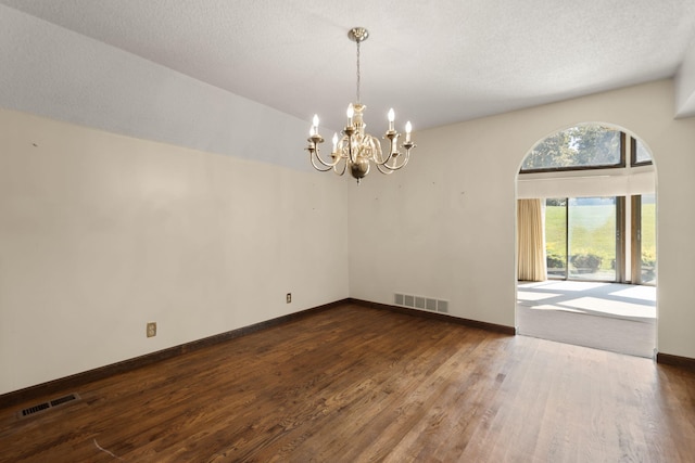 unfurnished room with dark hardwood / wood-style flooring, a notable chandelier, and a textured ceiling