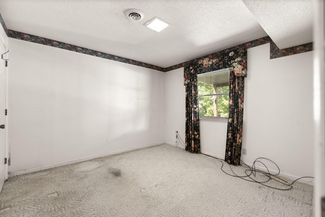 spare room featuring light colored carpet and a textured ceiling