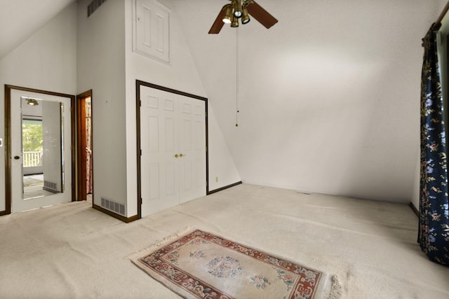 carpeted entrance foyer with ceiling fan and high vaulted ceiling