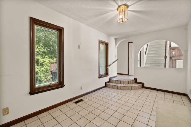 tiled spare room with a textured ceiling