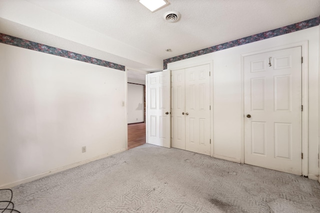 unfurnished bedroom featuring light carpet, a closet, and a textured ceiling