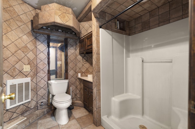 bathroom featuring toilet, heating unit, tile walls, and walk in shower