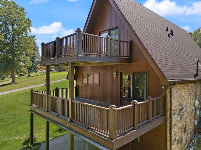 view of home's exterior featuring a balcony and a yard