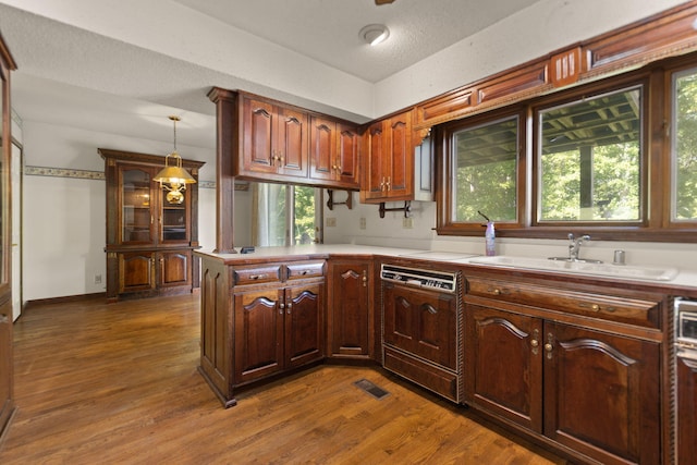 kitchen featuring sink, dark wood-type flooring, dishwasher, decorative light fixtures, and kitchen peninsula