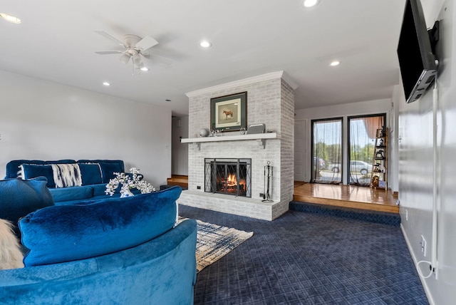 carpeted living room with a brick fireplace and ceiling fan