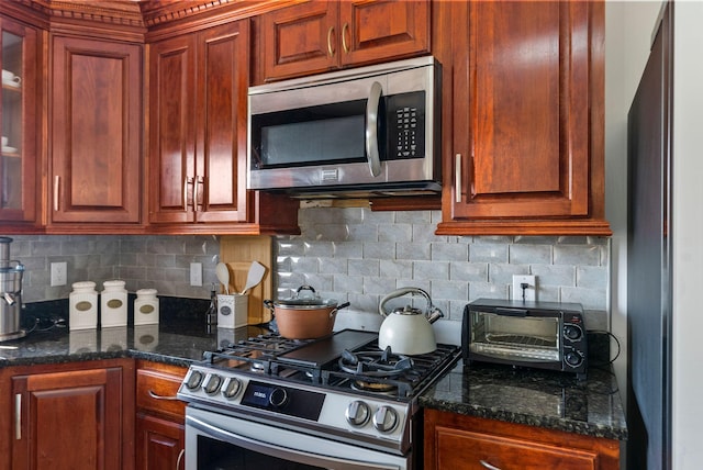 kitchen with dark stone countertops, stainless steel appliances, and backsplash