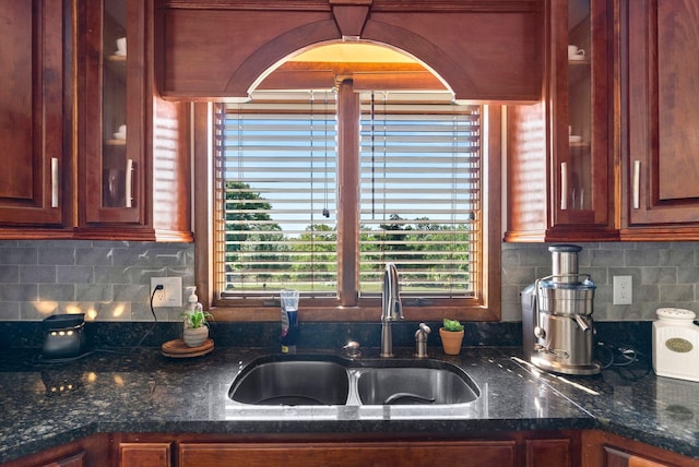 kitchen featuring dark stone counters, sink, tasteful backsplash, and a wealth of natural light