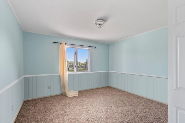 carpeted empty room featuring wood walls and ornamental molding