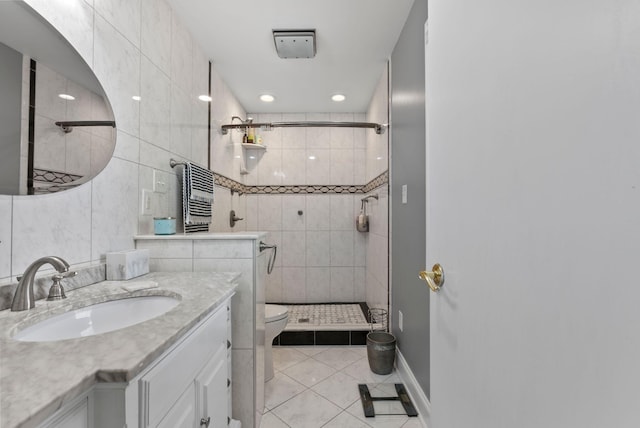 bathroom featuring tile walls, tiled shower, vanity, and toilet