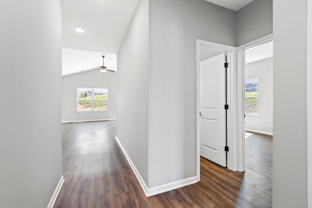 corridor with baseboards, dark wood finished floors, and vaulted ceiling