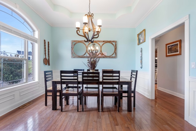 dining room featuring a wealth of natural light, an inviting chandelier, wood-type flooring, and a tray ceiling