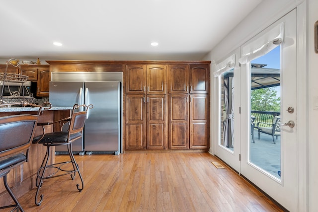 kitchen with stainless steel built in refrigerator and light hardwood / wood-style floors