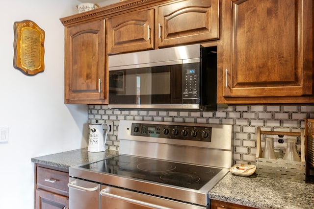 kitchen with light stone countertops, appliances with stainless steel finishes, and decorative backsplash