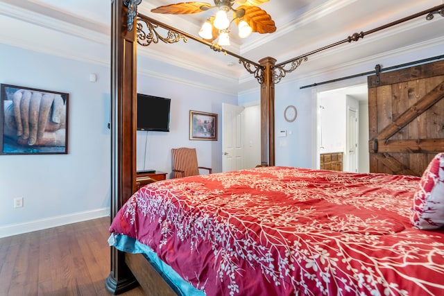 bedroom with ensuite bathroom, a barn door, dark wood-type flooring, ceiling fan, and ornamental molding