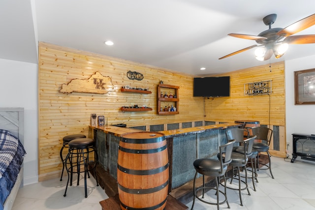 bar featuring wooden counters, a wood stove, wood walls, and ceiling fan