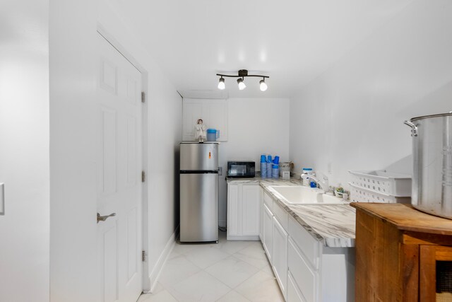 kitchen featuring white cabinets, stainless steel fridge, light tile patterned floors, and sink