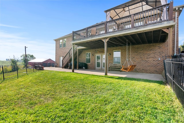 back of house with a deck, a lawn, and a patio