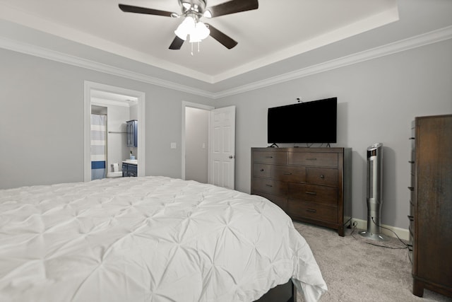 bedroom with light carpet, ensuite bathroom, a tray ceiling, crown molding, and ceiling fan