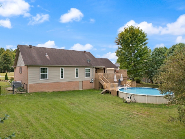 rear view of property featuring a pool side deck, a lawn, and central AC