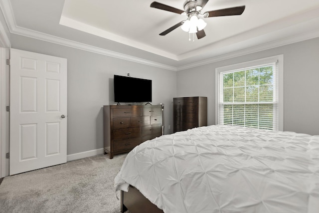 carpeted bedroom with a tray ceiling, crown molding, and ceiling fan